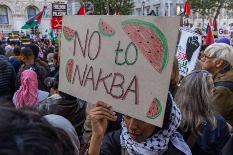 На плакате написано «Нет катастрофе». Под катастрофой (Nakba) обычно имеется в виду насильственное массовое переселение палестинцев в ходе арабо-израильской войны 1948 года
