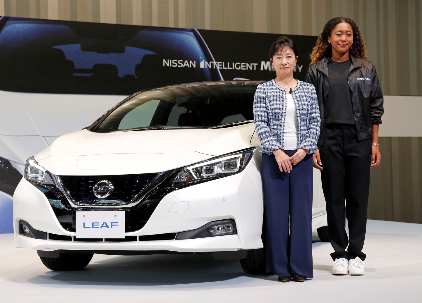 US Openi võitnud Naomi Osaka (paremal) ja  Nissani vanem asepresident Asako Hoshino poseerivad elektrilise Nissan Leafi kõrval.