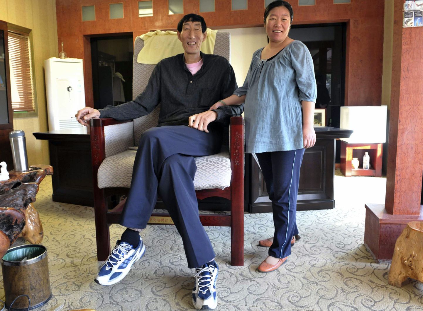 Bao Xishun (L), 57, a 2.36-metre (7 feet, 9 inches) herdsman listed by the Guinness World Records as the tallest living man, poses for photograph with his pregnant wife Xia Shujuan, 29, 1.68-metre (5 feet, 5 inches), at their apartment in Zunhua, Hebei province September 25, 2008. Guinness World Records has returned the title of world's tallest man to China's Bao after Ukrainian Leonid Stadnyk refused to be measured under new guidelines. Picture taken September 25, 2008. REUTERS/Stringer (CHINA).  CHINA OUT. NO COMMERCIAL OR EDITORIAL SALES IN CHINA.
