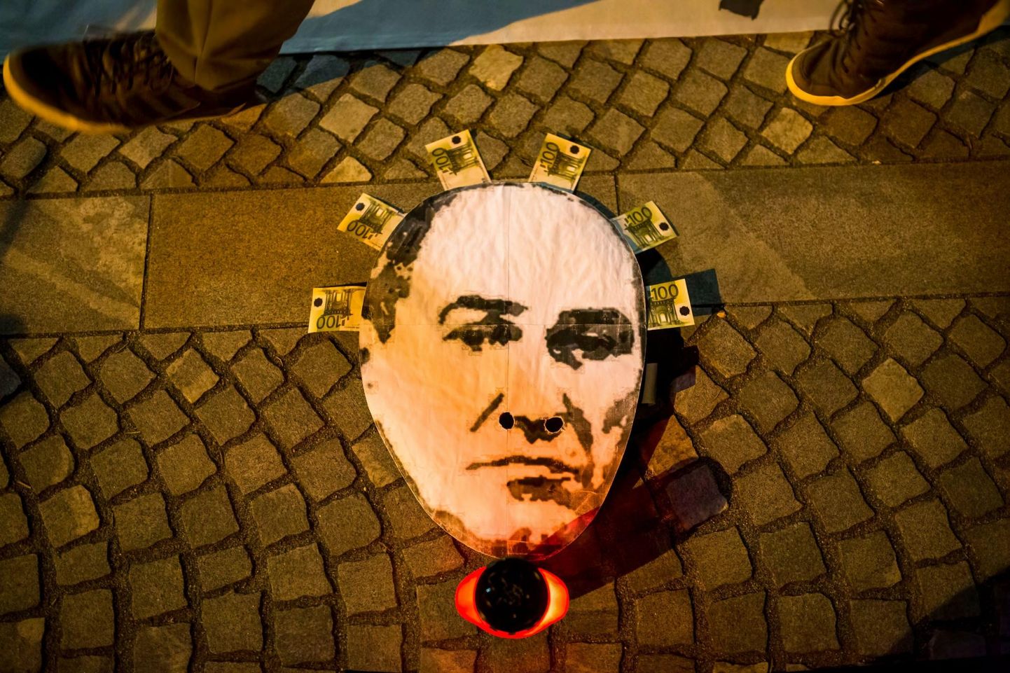 Sloveenia peaministrit Janez Janšat kujutav pabermask küünala kõrval maas valitsusvastasel meeleavaldusel Ljubljanas veebruari keskel. 