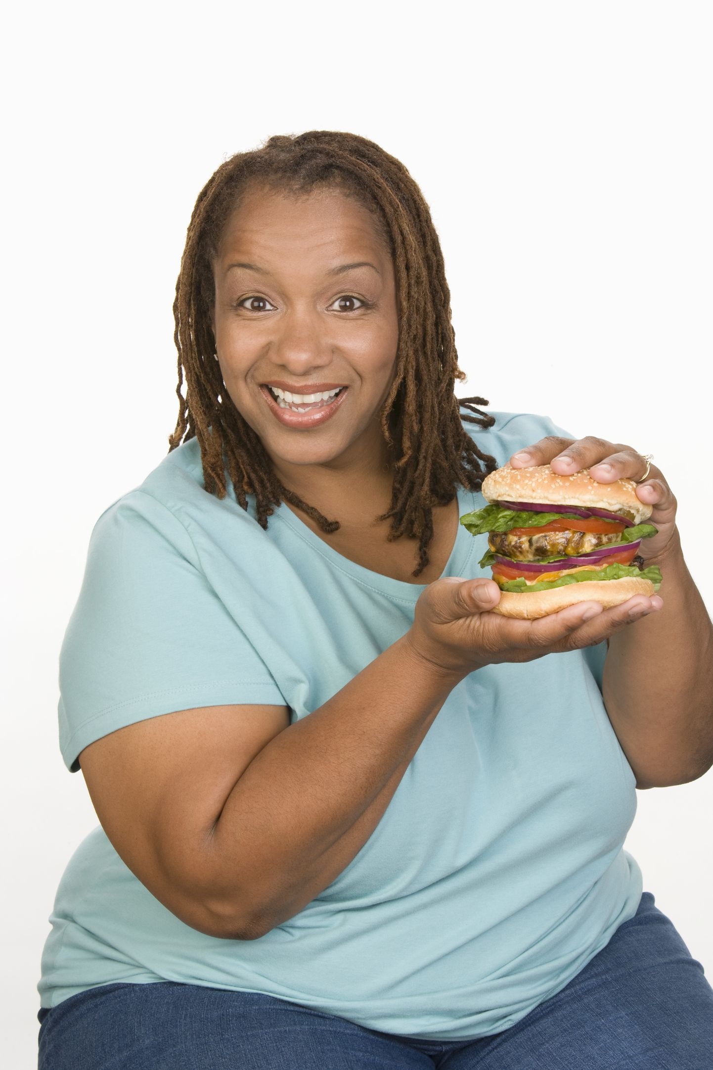 Полная женщина ест гамбургер. Иллюстративное фото.