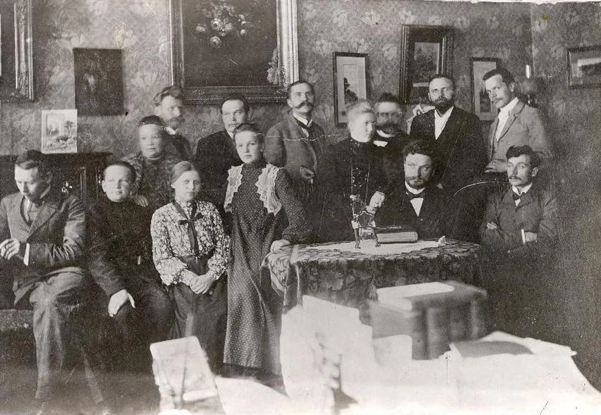 “Teataja” toimetuse liikmed 1904 M.Martna korteris: laua ääres paremal (istuvad) M.Pung ja M.Martna; seisavad (paremalt): Th.Ussisoo, H.Laipman, J.V.Veski, Paulberg, E.Vilde, K.Päts ja H.Pöögelmann nende ees Martna lastega, vasakult äärmine N.Virgo.