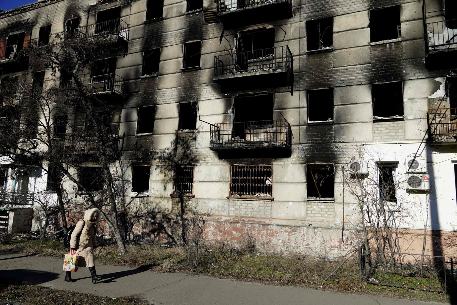 TOPSHOT - A woman walks past a destroyed apartment block in the Russian-controlled town of Severodonetsk in the eastern Lugansk region on January 24, 2023. (Photo by STRINGER / AFP)