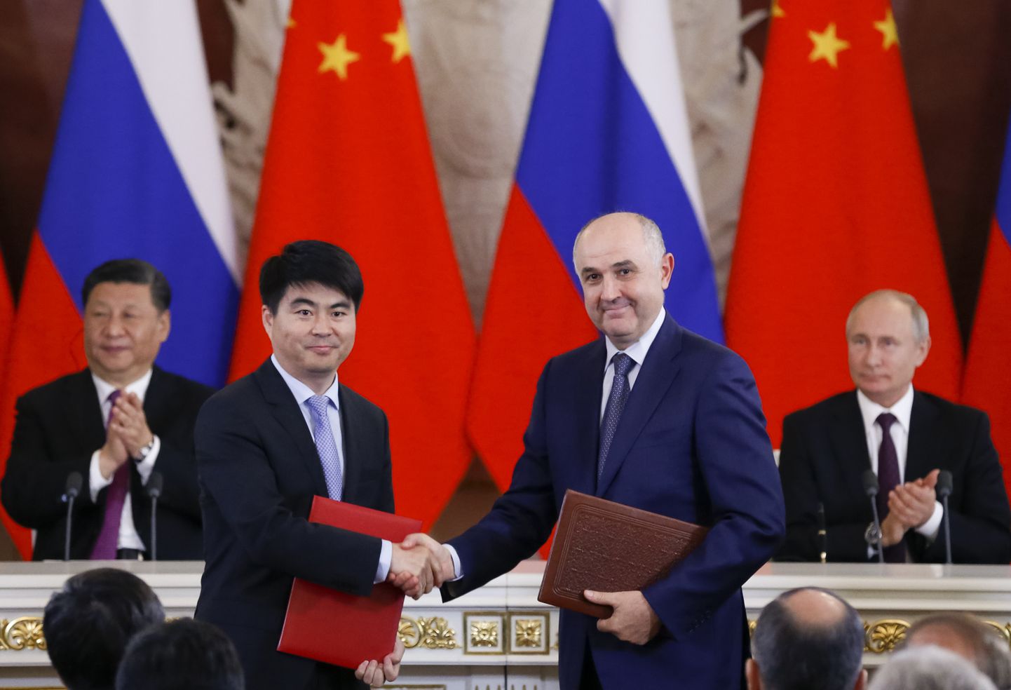 Huawei nõukogu aseesimees Guo Ping surub kätt Venemaa mobiilioperaatori MTS juhiga Alexei Kornyaga. Taustal on Hiina president Xi Jinping ja Venemaa president Vladimir Putin.