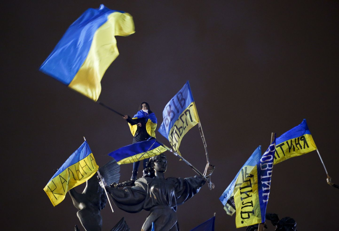 A Pro-European integration protester waves a Ukrainian national flag as she stands on a statue during a mass rally at Independence Square in Kiev December 15, 2013. Thousands massed on Sunday for a rally against President Viktor Yanukovich just days before he heads for a meeting at the Kremlin which the opposition fears will slam the door on integration with the European mainstream.   REUTERS/Marko Djurica (UKRAINE  - Tags: POLITICS CIVIL UNREST)