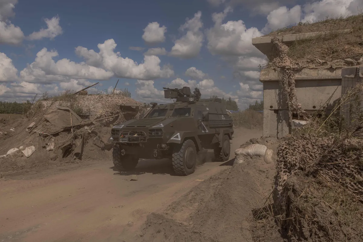 A Ukrainian military vehicle driving past a destroyed border crossing point with Russia, in the Sumy region.