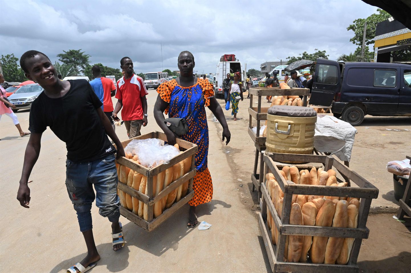 Уличные торговцы несут корзины с хлебом в Абиджане, столице Кот-д'Ивуара. Правительство страны установило верхний предел цен на некоторые продукты питания, такие как пшеничная мука.