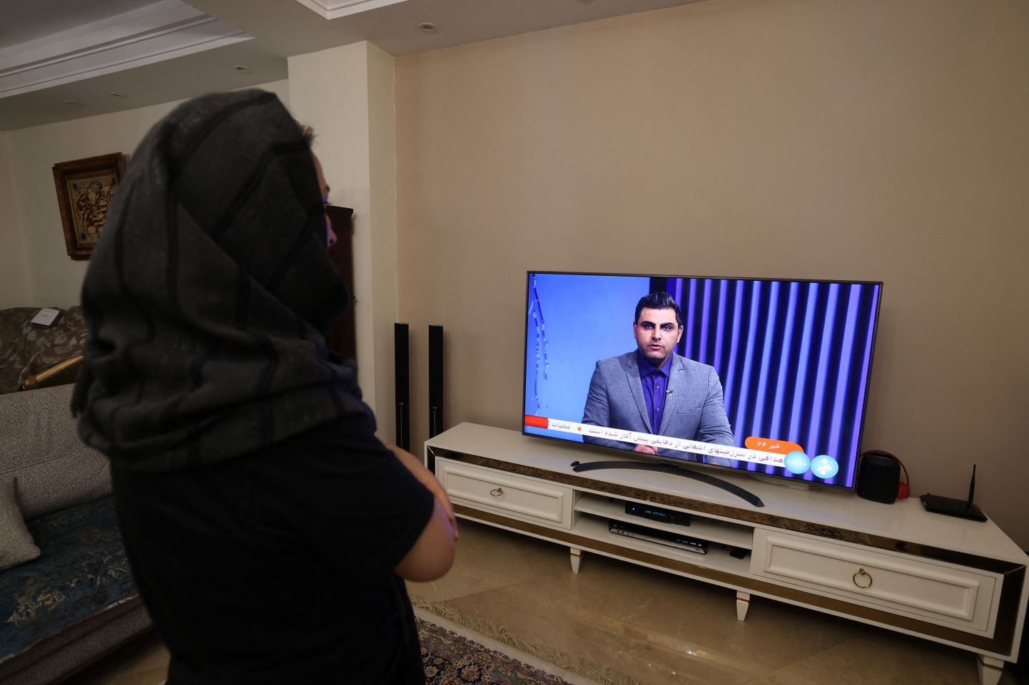 Sieviete Irānā skatās televīzijas pārraidi, kurā tiek vēstīts par Irānas uzbrukumu Izraēlai