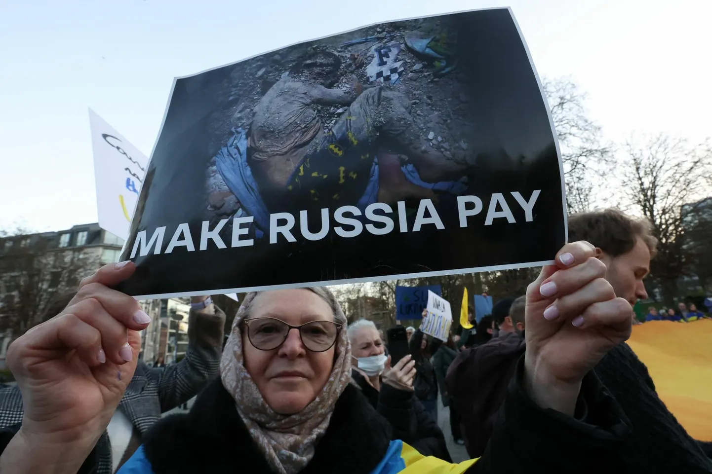 Meeleavaldaja Brüsselis plakatiga, mis kutsub üles panema Venemaad maksma sõja eest Ukrainas.