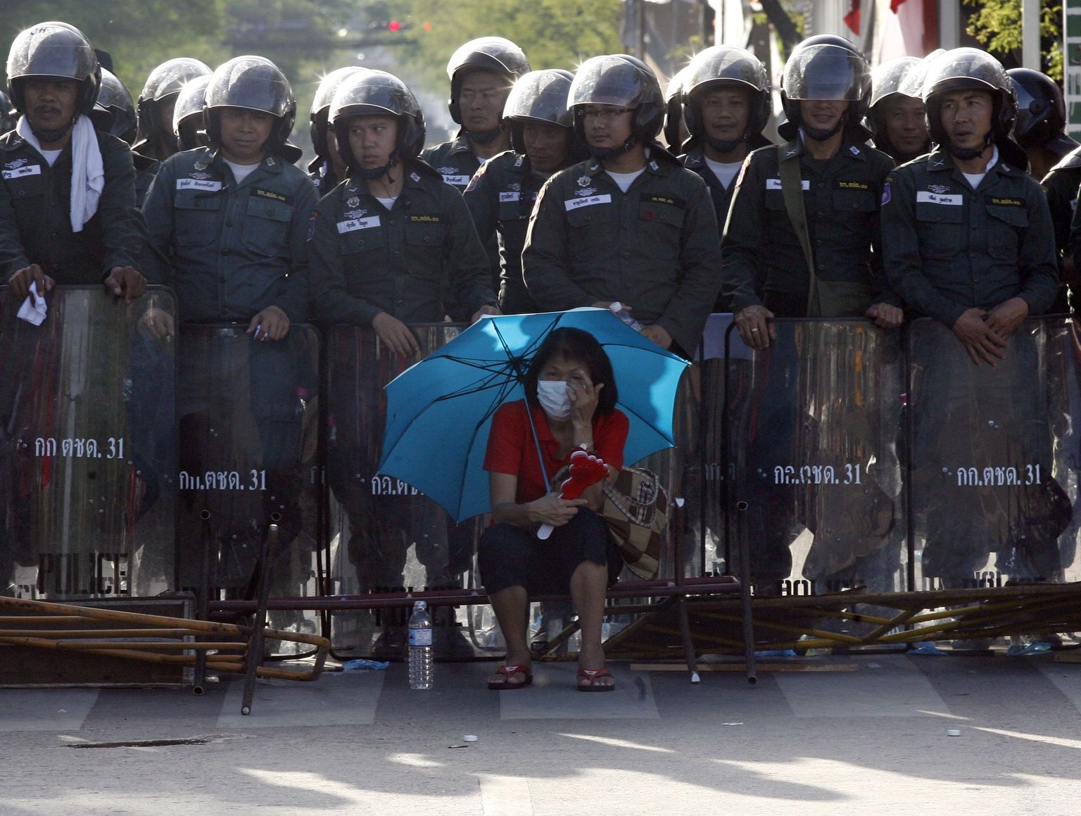 Участница акций протеста и полицейские в заграждении на улице Бангкока.