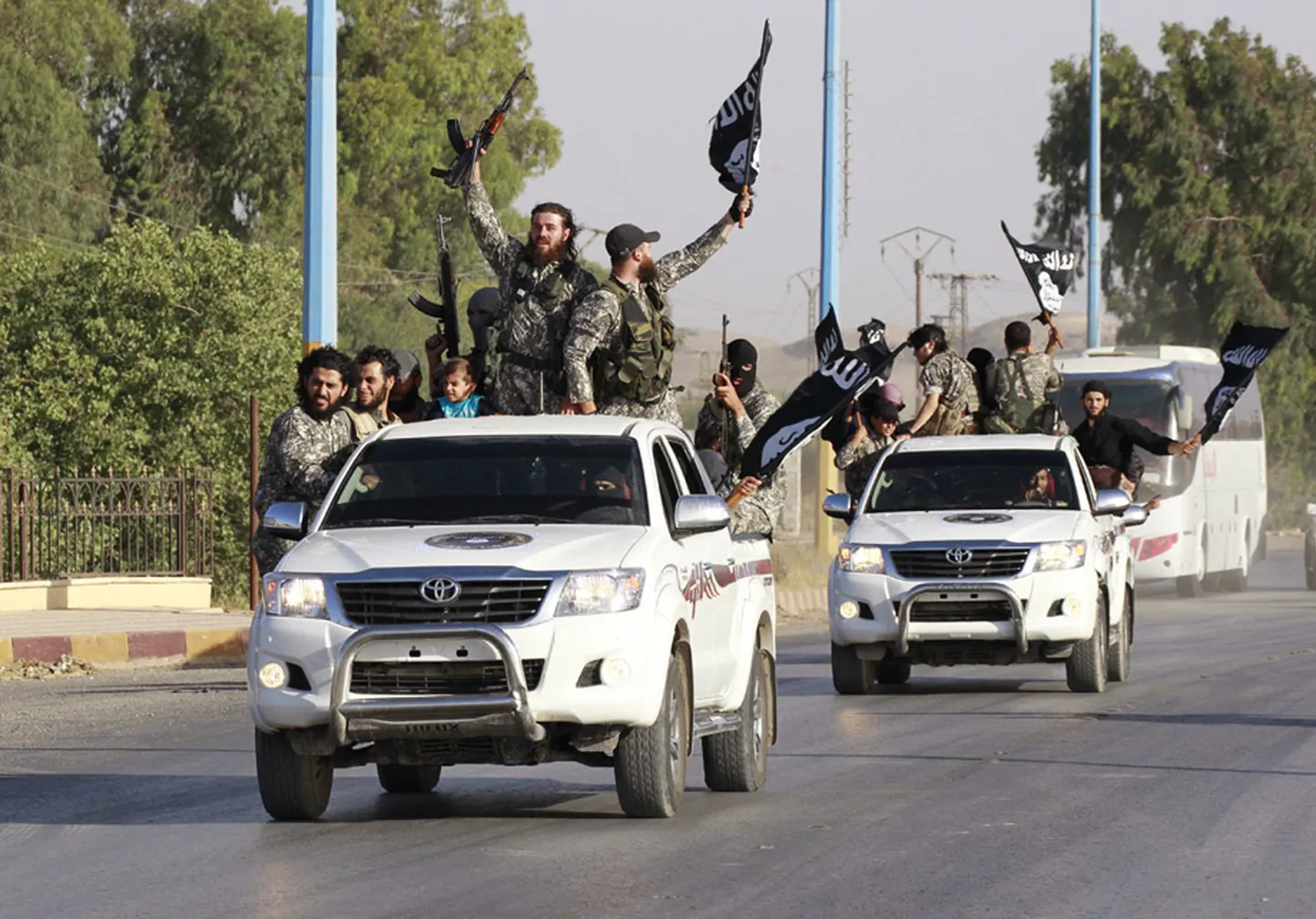 Islamiriigi võitlejad lehvitamas lippe sõjaväeparaadil Süüria Raqqa provintsi tänavatel 2014. aastal.