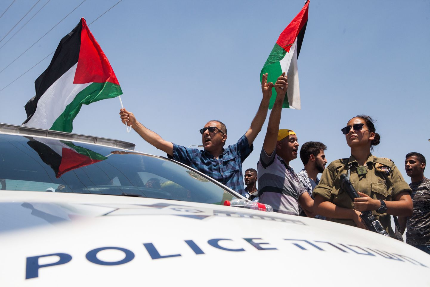 Palestiina lipuga mees Iisraeli politseiauto kõrval.