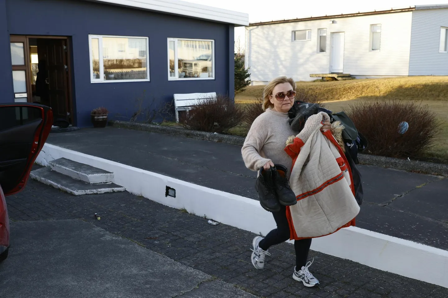 Eile mõneks minutiks koju pääsenud Grindavíki elanik kandmas laavapurskest ohustatud kodust välja rõivaid ja jalanõusid. 