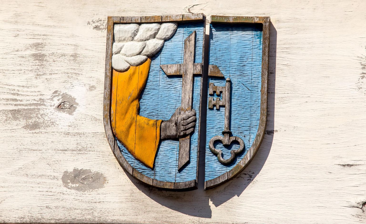 Pildil on Pärnu vapp, millel kujutatakse preestri käes olevat risti, kõrval linnavärvava võti.