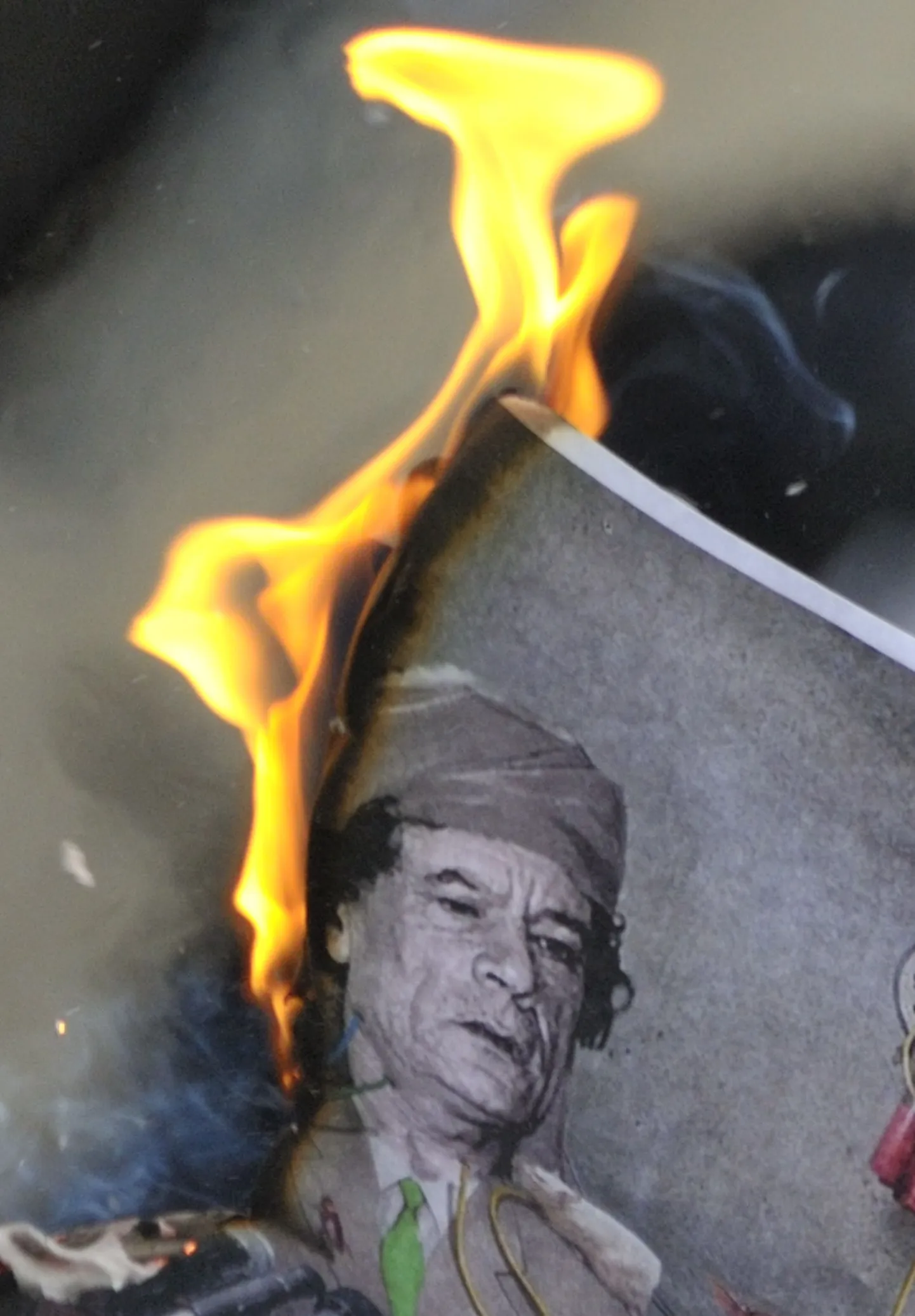 Повстанцы подожгли портрет Муамара Каддафи.
