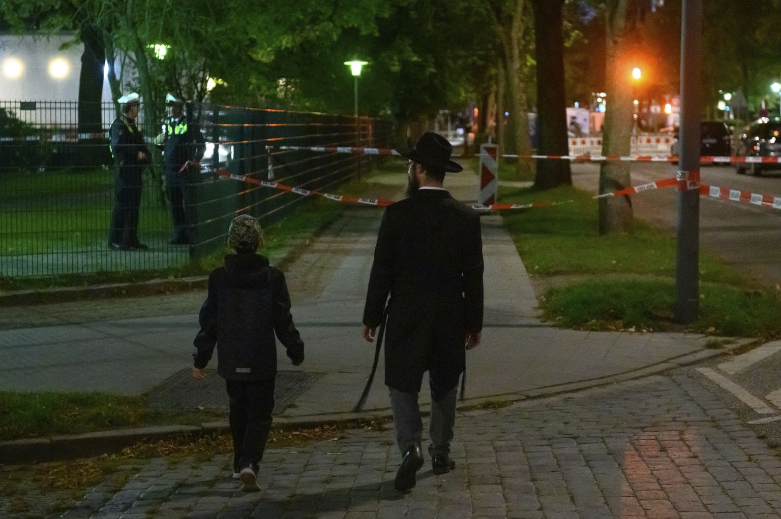 Mees ja poiss jalutavad politsei sisse piiratud Hamburgi sünagoogi juures.