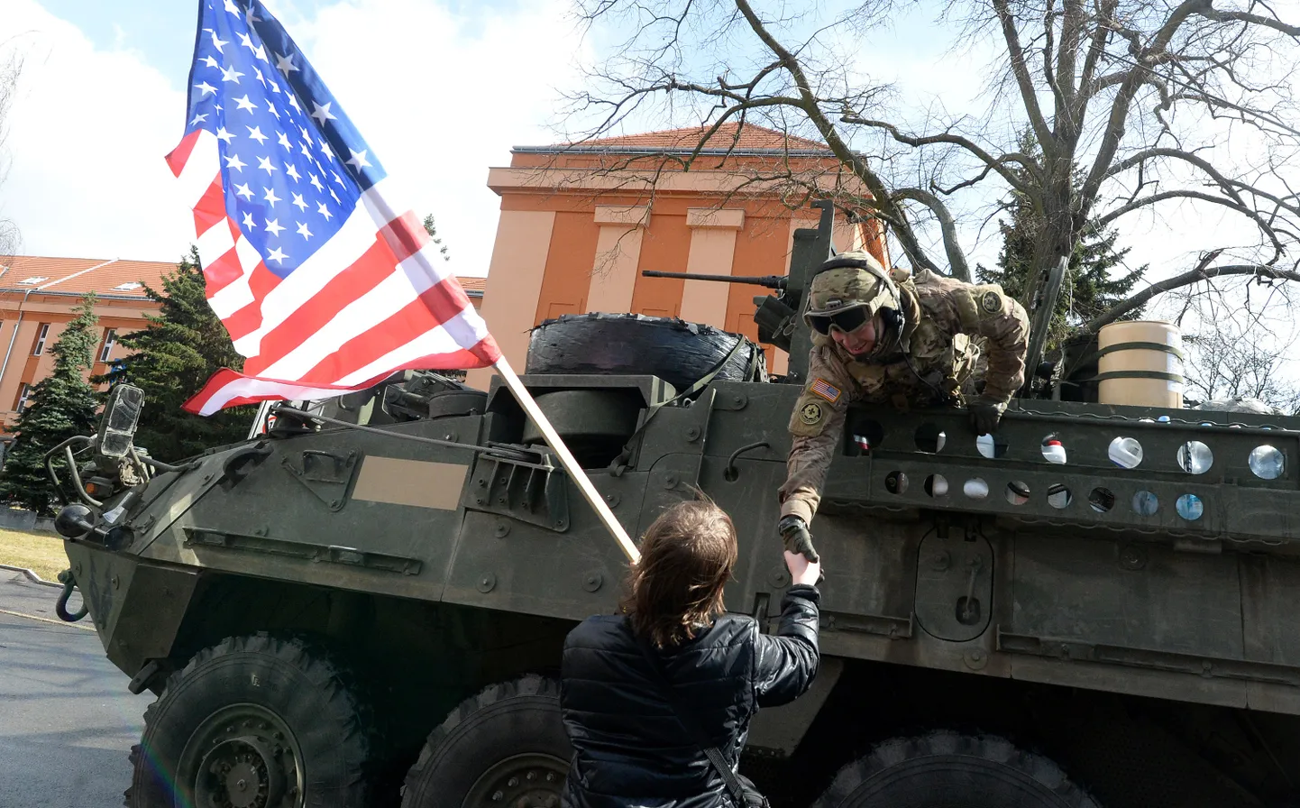 USA sõdur surub kätt Tšehhi elanikult, kes hoiab USA lippu, 30. märtsil 2015. USA sõjaväekolonn, mis alustas liikumist Baltimaadest ja lõpetas Saksamaal, sai teel paljude kohalike tervituse osaliseks. Pilt on illustratiivne.