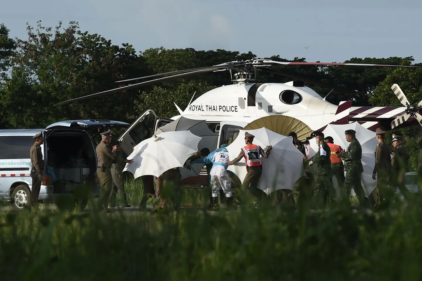 Politseinikud ja sõjaväelased katavad päikesevarjudega kanderaami, kui ühte Tham Lunagi koopast päästetud poissi toimetatakse eile kopteri pardale, mis lennutas ta Chiang Rai provintsi haiglasse.