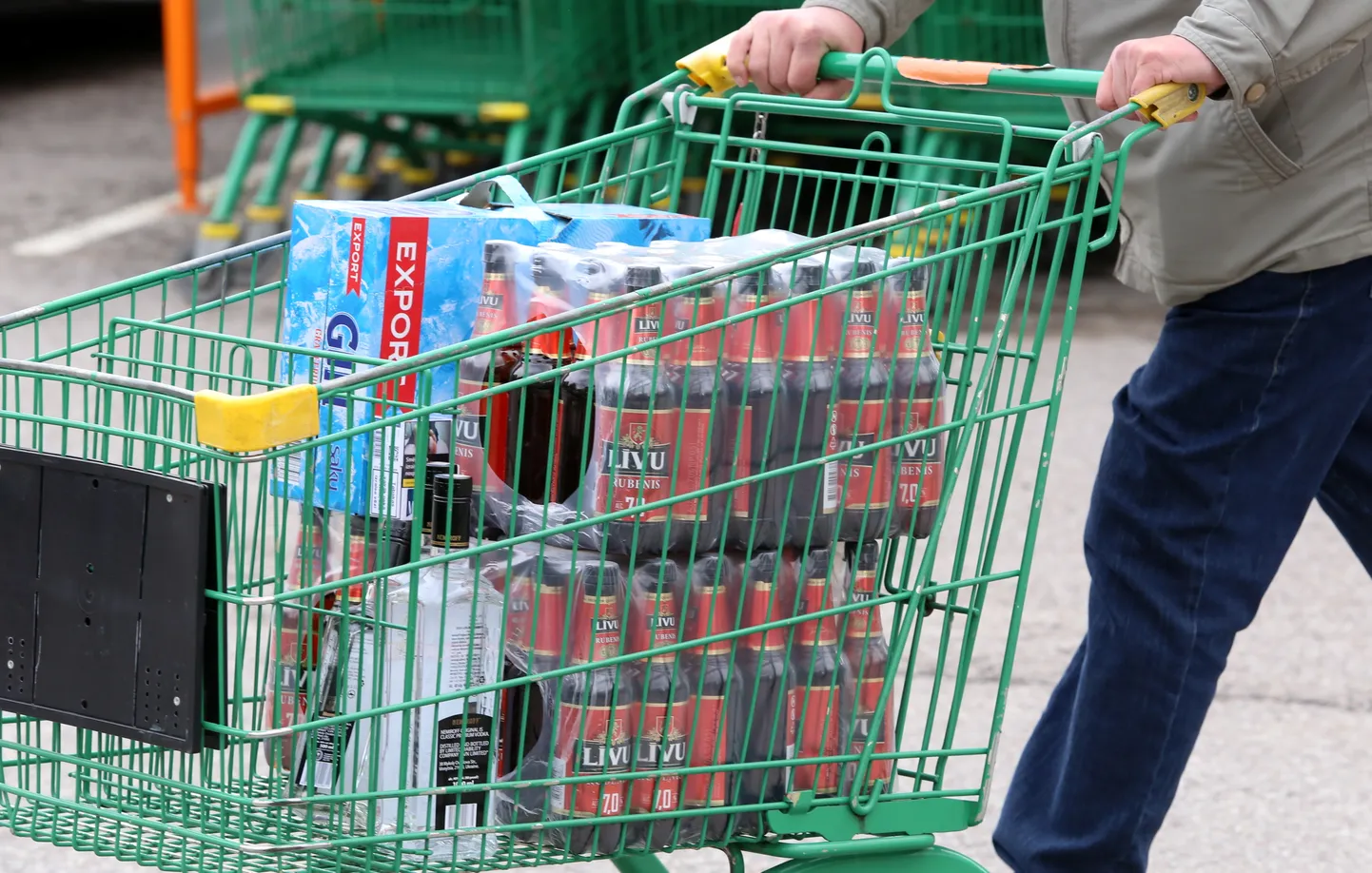 Cilvēks ar iepirkumu ratiņiem pie dzērienu veikala "Alko 1000 Market" Valkā