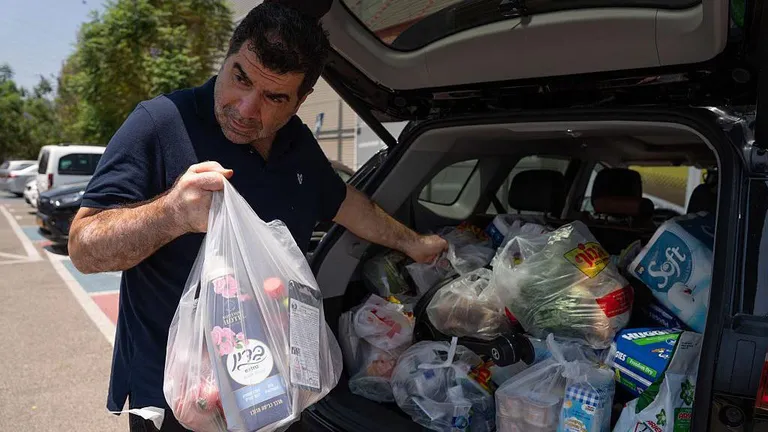 Мужчина в Тель-Авиве закупается продуктами и водой на фоне опасений ответного удара Ирана.
