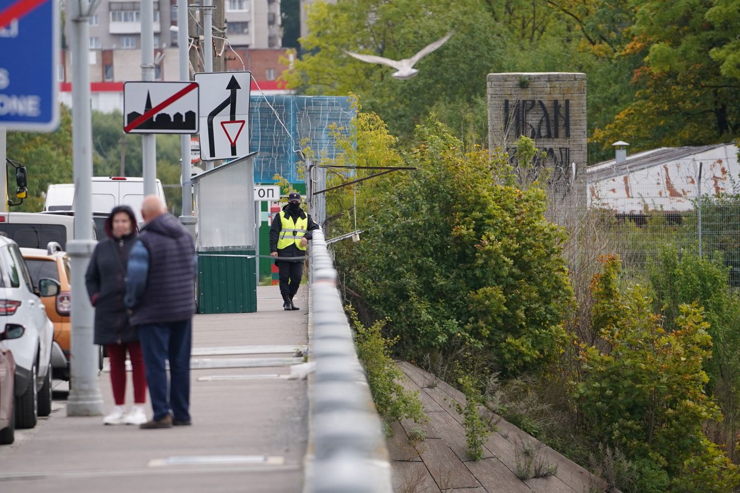 Погранчник РФ смотрит в сторону Эстонии, пока люди ждут в очереди въезд в Россию через реку Нарова на мосту между Нарвой и Ивангородом, сентябрь 2022 года.