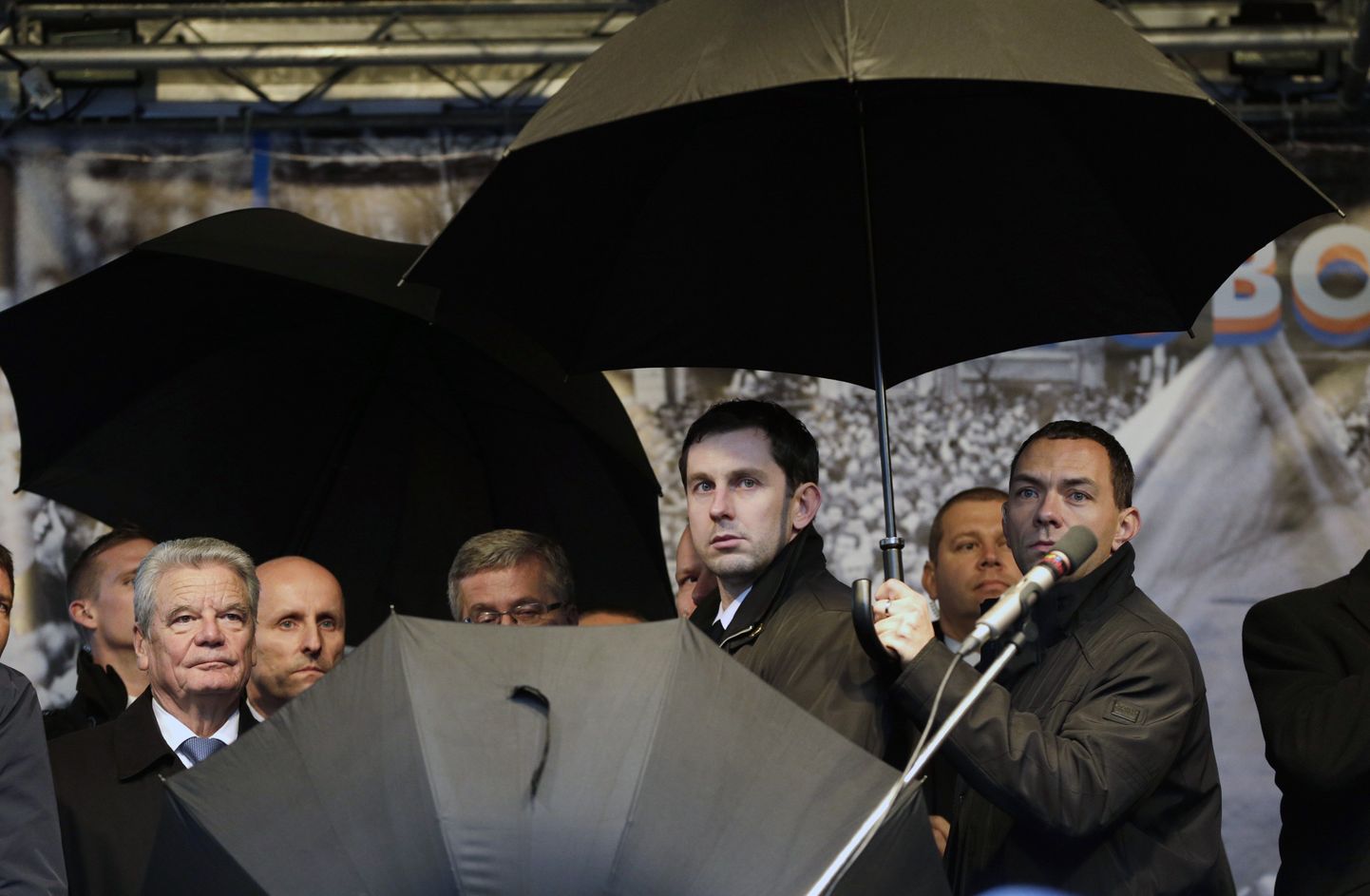 Julgeolekutöötajad kaitsmas vihmavarjudega Saksamaa presidenti Joachim Gaucki (vasakul)