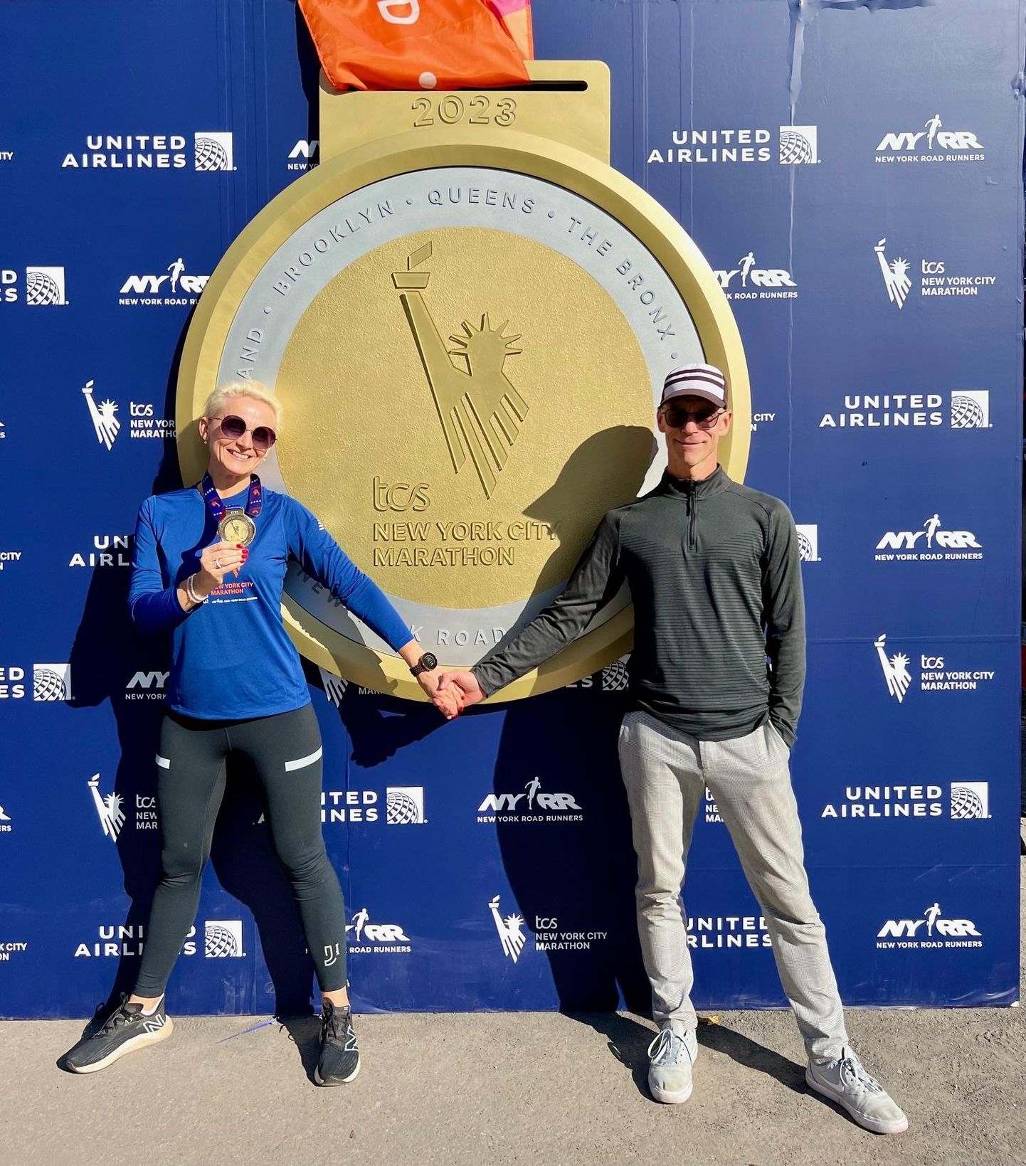 Signe Ventsel, välja teenitud kuldne medal kaelas, koos kaasa Marko Pavloviga New Yorgi maratoni sümbolmedali juures.