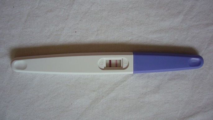 Положительный тест на беременность в руках у женщины