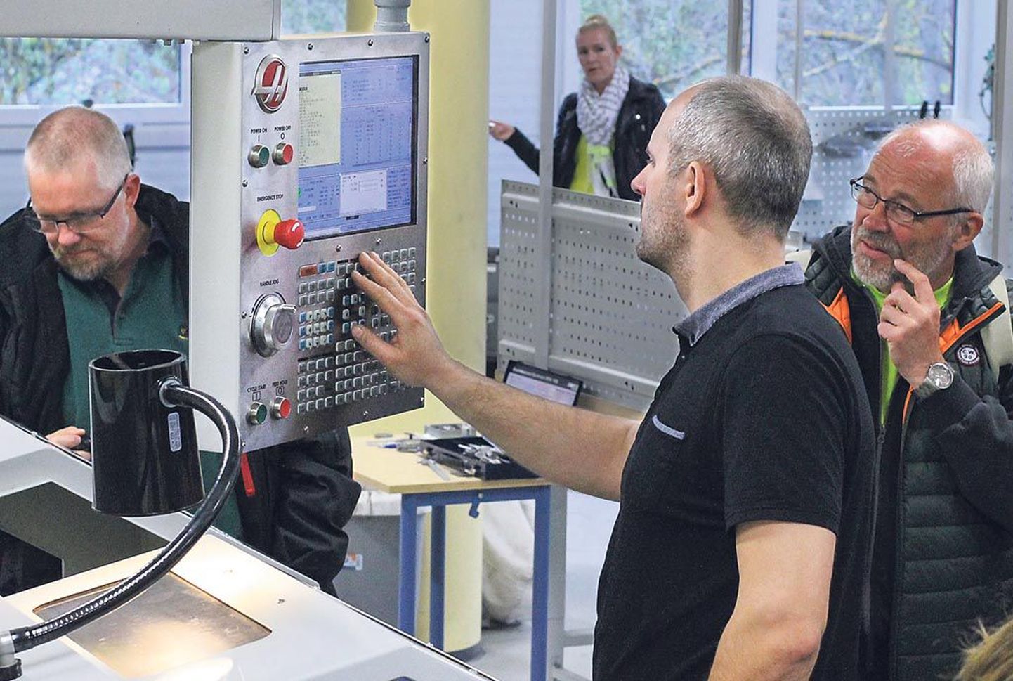 Pärnumaa kutsehariduskeskuse auto- ja metalliõppetöökoja juhataja Taivo Kaelep näitab külalistele, kuidas programmeeritavat CNC-tööpinki kasutada.