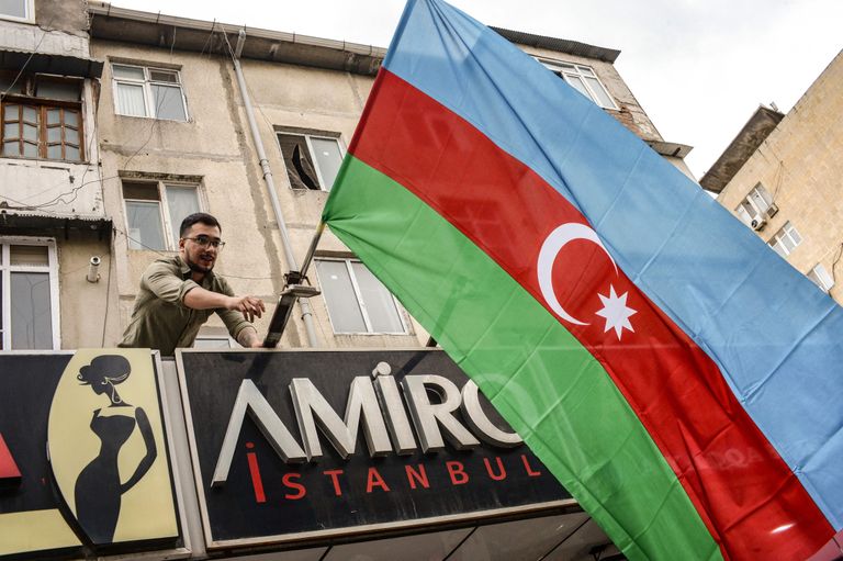 Житель столицы Азербайджана вывешивает государственный флаг в Баку 20 сентября 2023 года в поддержку наступления в Нагорно-Карабахском регионе.