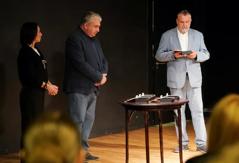 Aktieris Gundars Āboliņš un aktrise Anna Nele Āboliņa sveic Latvijas Leļļu teātra režisoru, dramaturgu un dziesmu tekstu autoru Valdi Pavlovski ar Veras Singajevskas vārdā nosaukto balvu par nozīmīgu ieguldījumu bērnu un jauniešu teātra mākslas attīstībā.