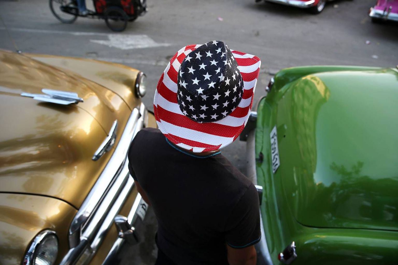 Kuuba mees autode vahel Havannas, Ameerika kaabu peas.