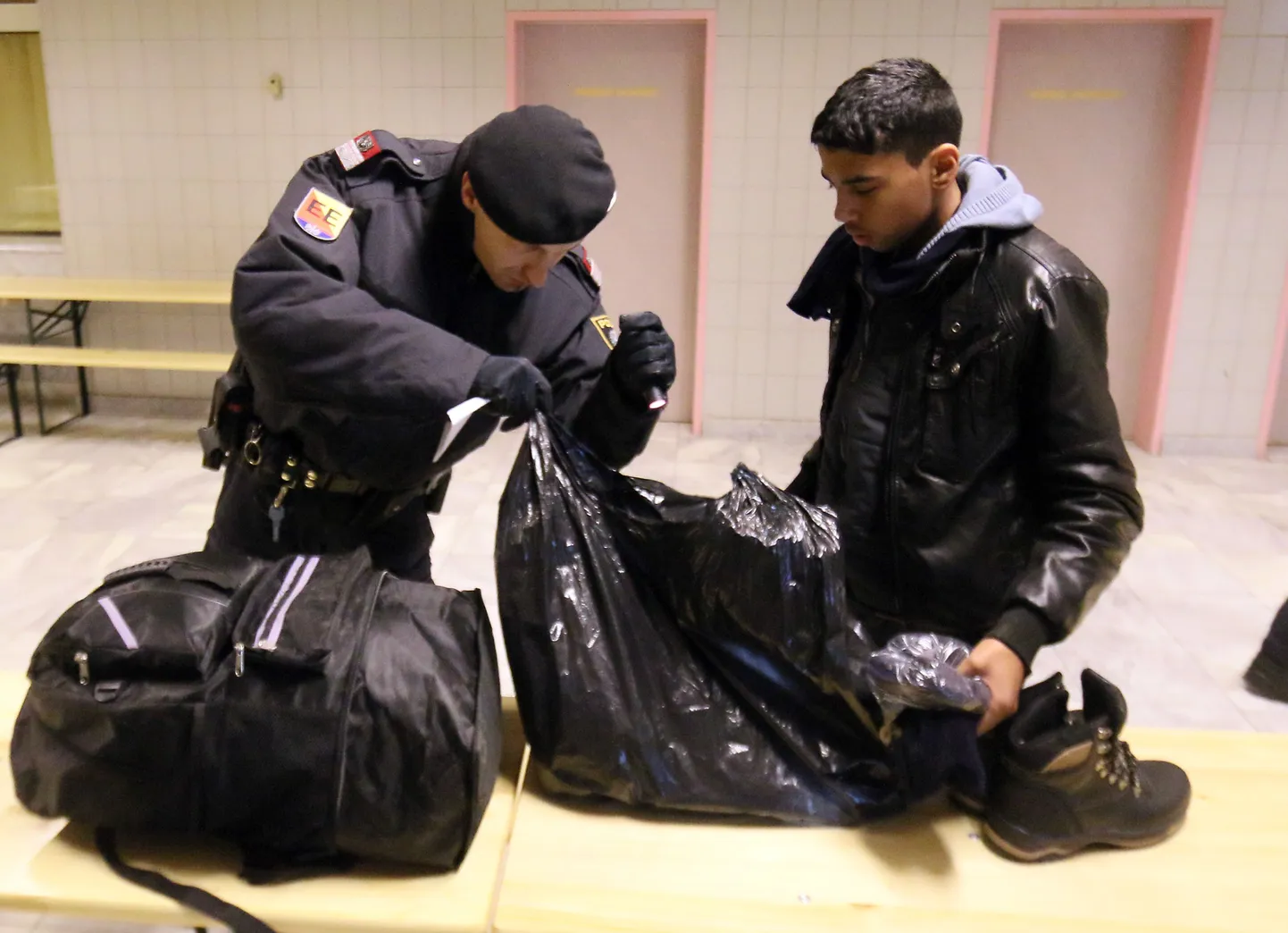 Austria politseinik Sloveeniast saabuva migrandi kotti kontrollimas.