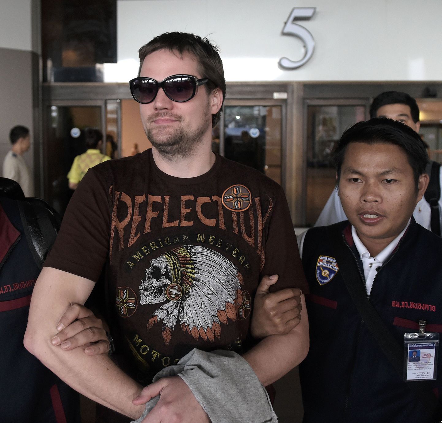 Swedish co-founder of the Pirate Bay website Fredrik Neij (L), 36, is taken by Thai immigration police officers at Don Mueang airport, to an immigration detention centre in Bangkok on November 5, 2013. The Swedish co-founder of the Pirate Bay website is due to be hauled to Bangkok following his arrest in northeast Thailand, with police from Stockholm waiting to press for his deportation to serve a jail term for copyright infringement. AFP PHOTO/ Nicolas ASFOURI