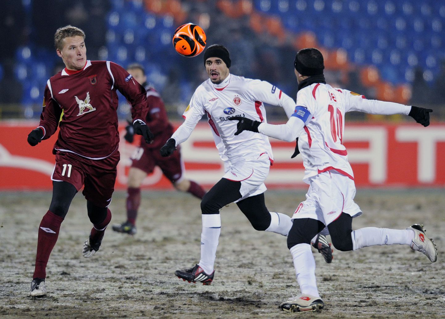 Александр Бухаров (слева) ведет борьбу за мяч с футболистами "Хапоэля".