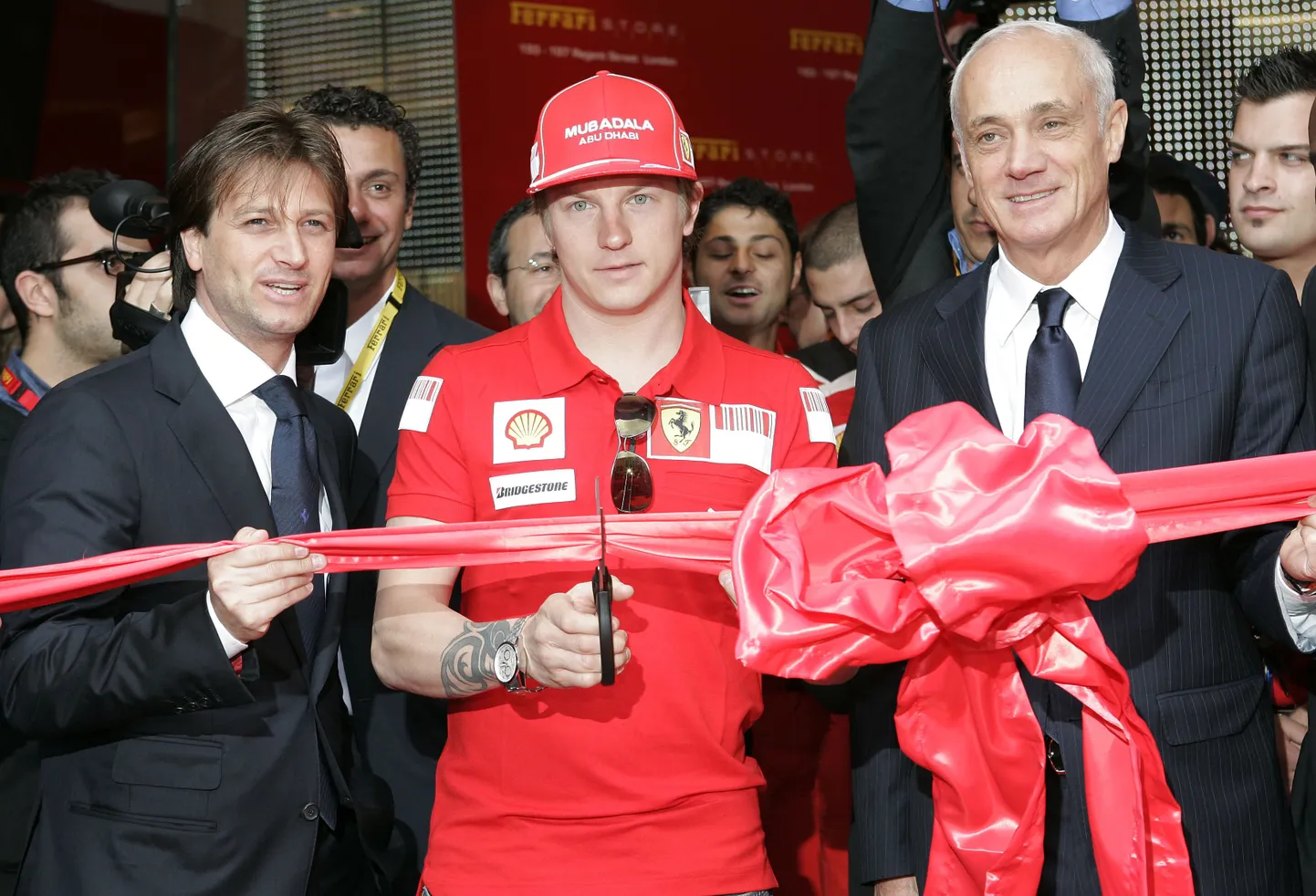 Kimi Räikkönen  koos Ferrari Global asepresidendi Danny Bahari (vasakul)ja Ferrari poe ühe omaniku Antonio Percassiga punast linti läbi lõikamas
