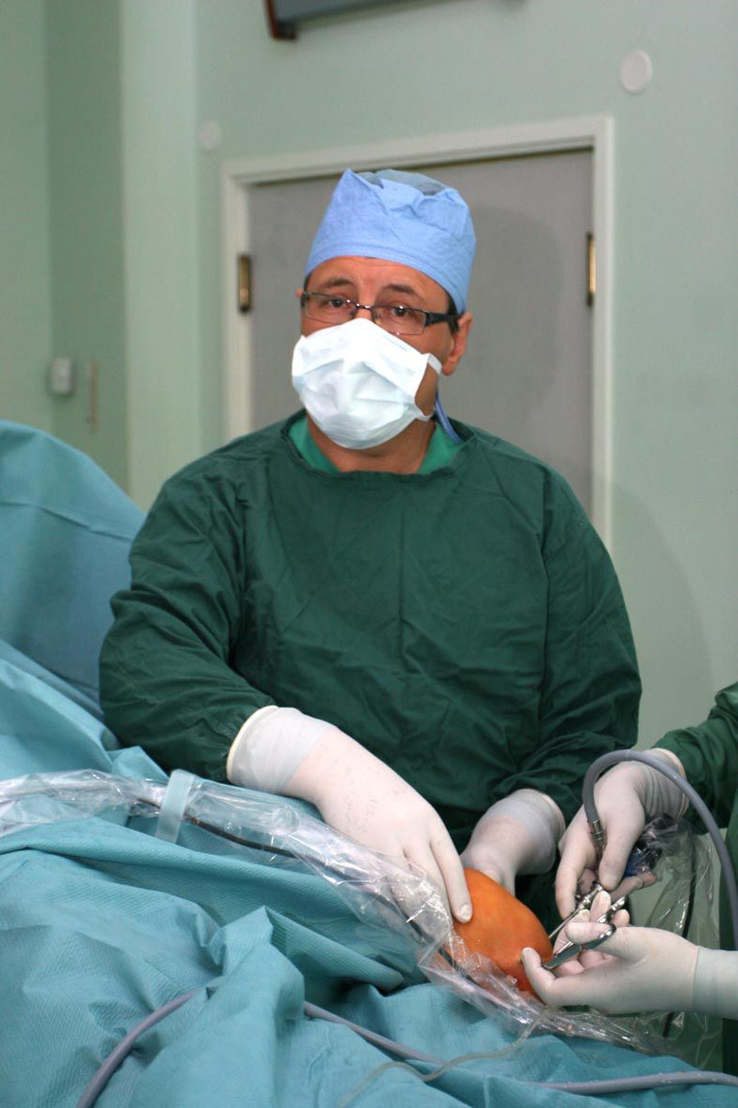 Rohelise kostüümi ja valge maski taga tegutsev Järvamaa haigla kirurg Mihhail Feštšin on 25 aasta jooksul terveks ravinud paljusid patsiente. Pildil on ta abiks põlveoperatsioonil.