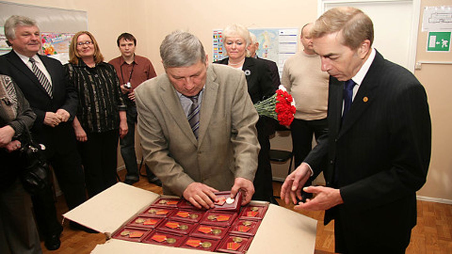 Foto 2010. aastast, kus tollane Venemaa suursaadik Nikolai Uspenski annab Valeri Tumkole (keskel) üle kohalikele veteranidele jagamiseks mõeldud medalid nn Suurest Isamaasõjast 65 aasta möödumise puhul.