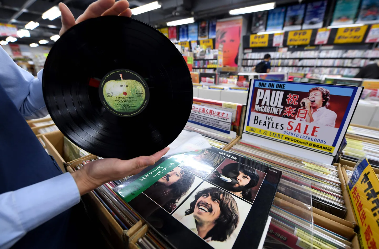 Poemüüja näitab Jaapanis toodetud viimase Beatlesi stuudio albumi vinüüli / AFP PHOTO / Toshifumi KITAMURA