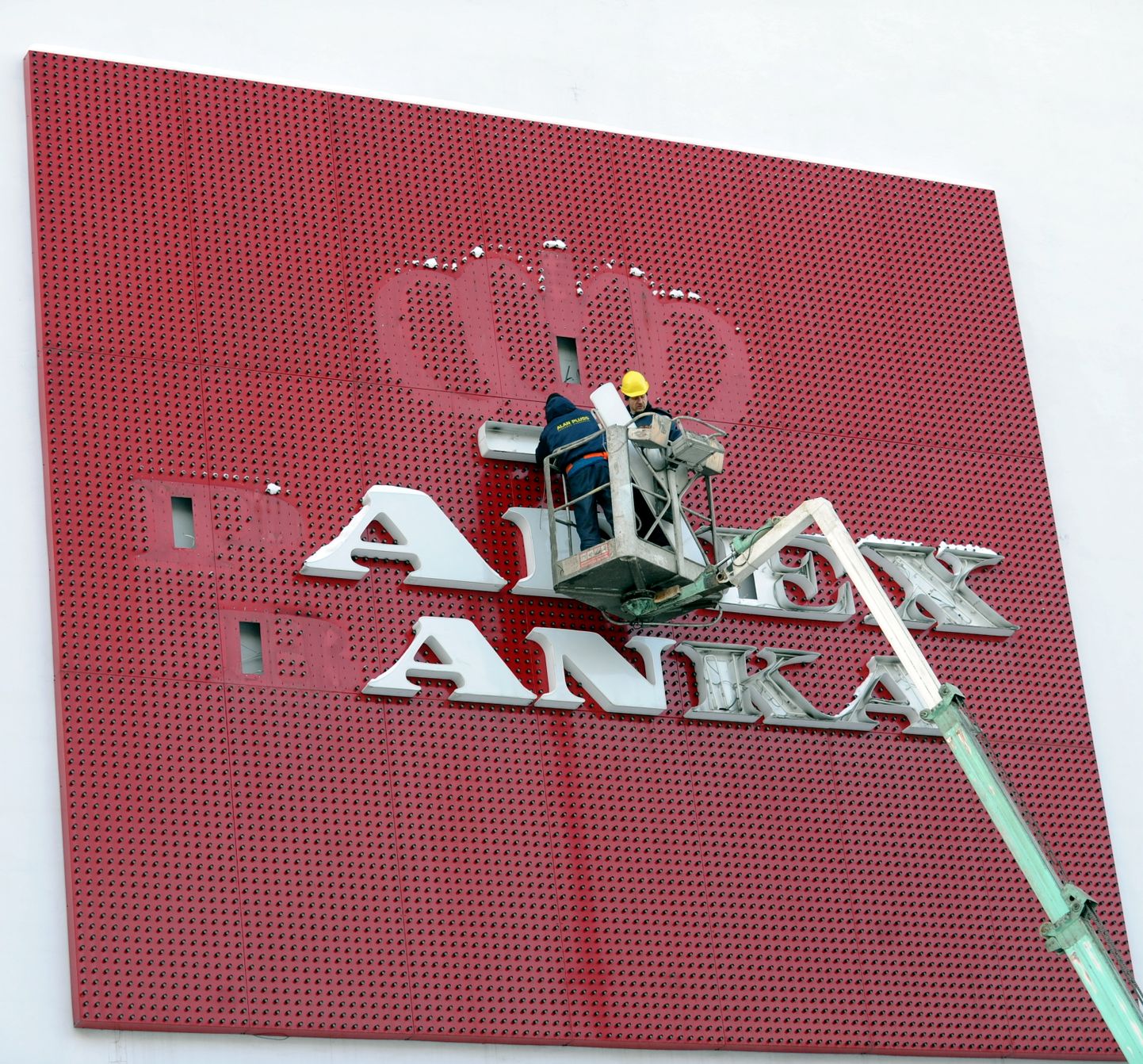 SIA "Alan Pluss" darbinieki noņem "Parex bankas" reklāmu no mājas sienas Brīvības ielā.