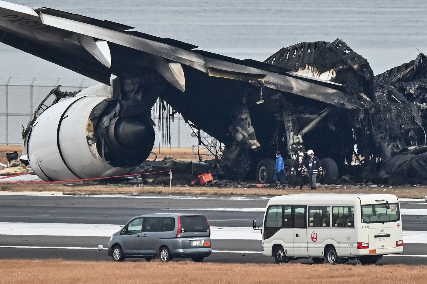 Ametnikud vaatamas Japan Airlinesi (JAL) reisilennuki põlenud rususid Tokyo rahvusvahelises lennujaamas Tokyos Haneda asfaldil 3. jaanuaril 2024, hommikul pärast seda, kui JALi reisilennuk põrkas vastu väiksemat rannavalvelennukit. Viis Jaapani rannavalve lennuki pardal olnud inimest hukkus 2. jaanuaril.