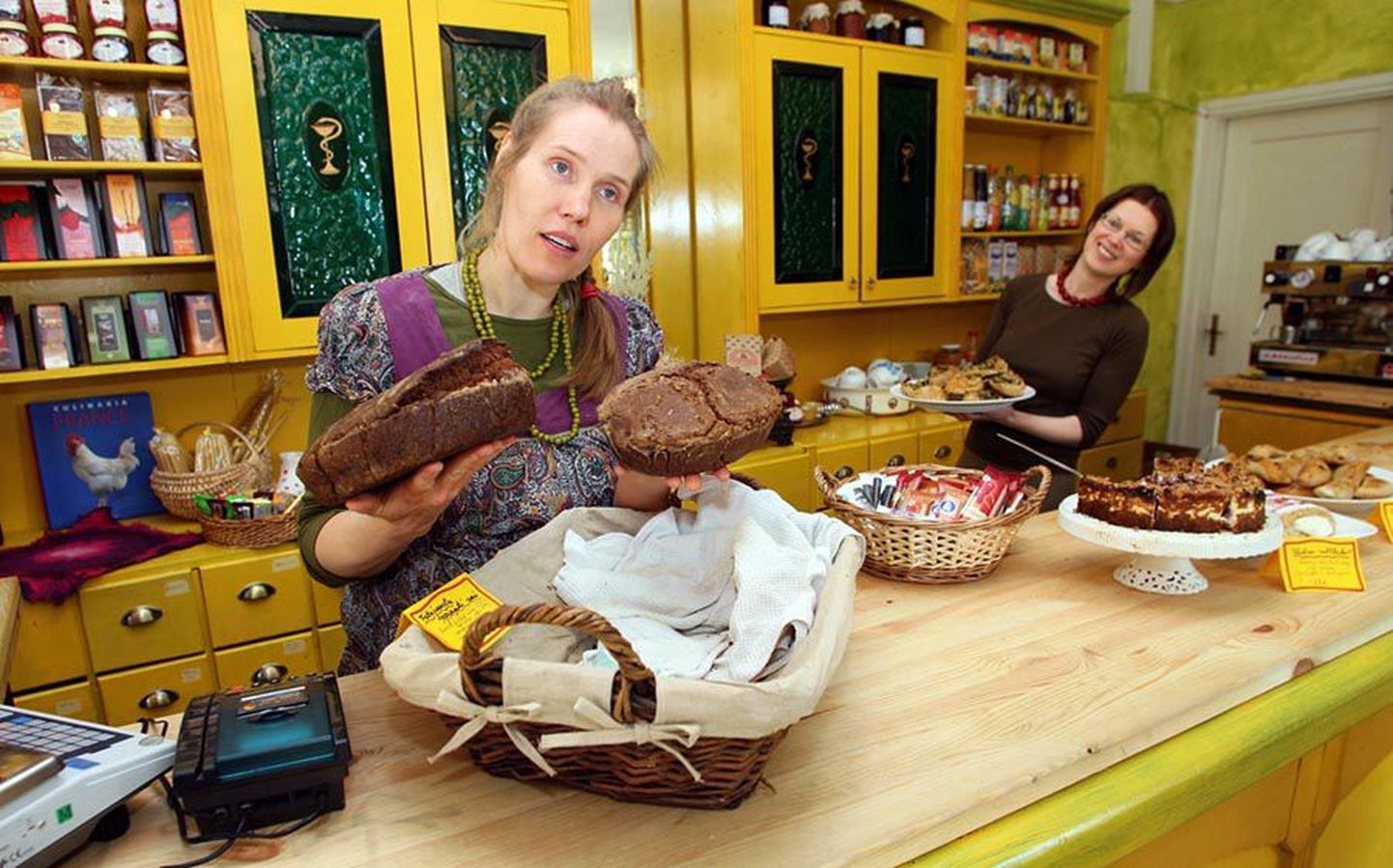 Mahekohviku looja Kaari Onni (esiplaanil) näitab omaküpsetatud leibu. Tema selja taga toob müüja Margit Kuhi letile vaagnat naadi-juustusaiakestega.