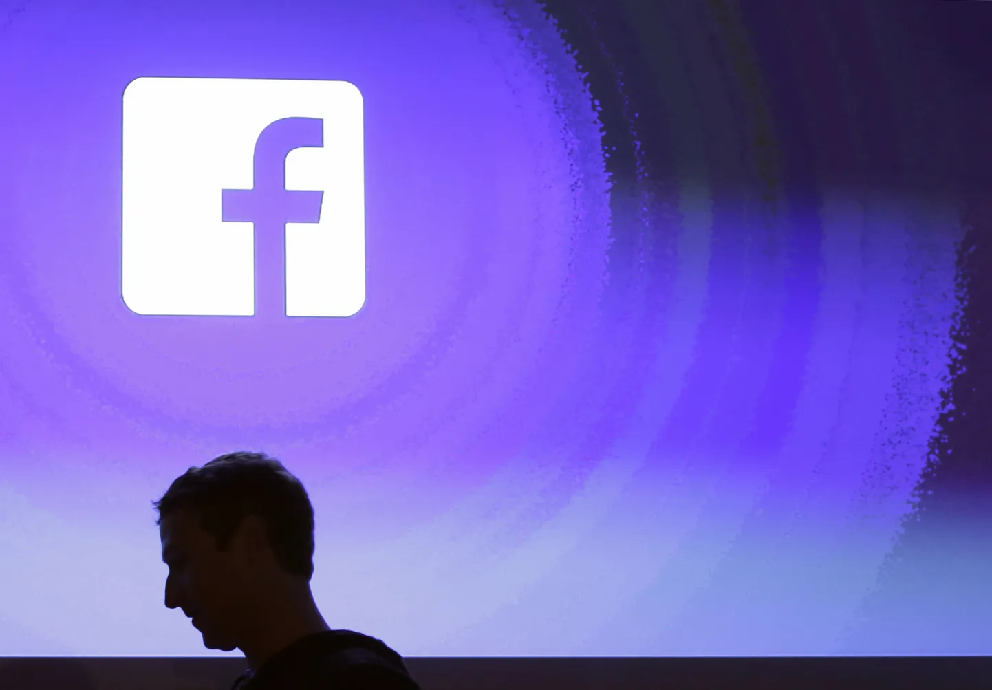 Facebook juht Mark Zuckerberg ettevõtte logo taustal.