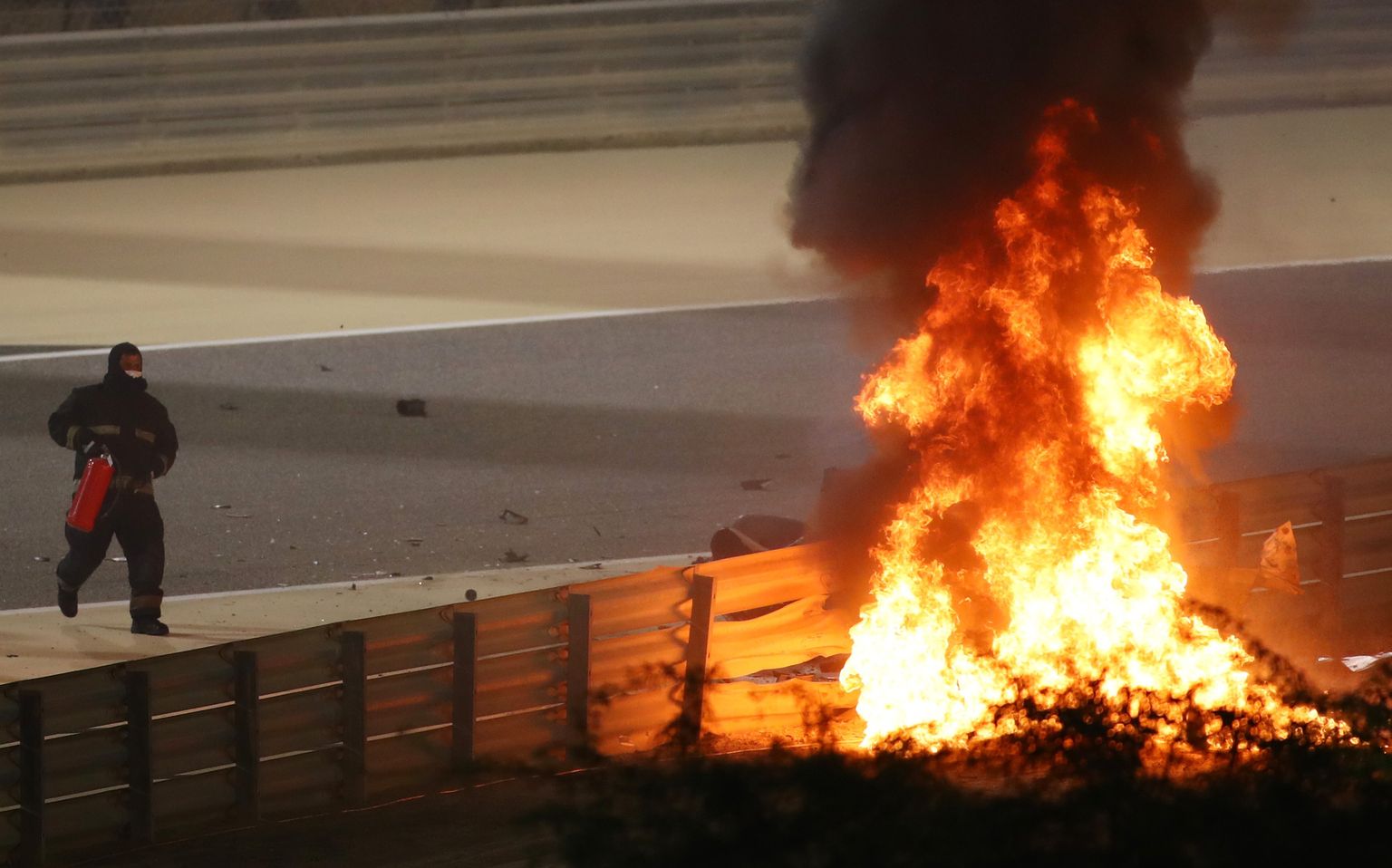 Pildil sööstab rajajulgestaja tulekustutiga Romain Grosjeani põleva vormeli suunas.