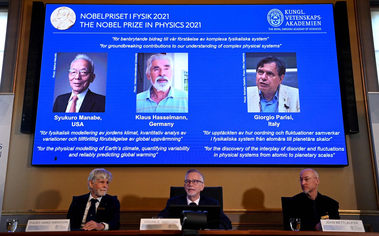 2021. aasta Nobeli füüsikaauhinna laureaadid vasakult ekraanil: Syukuro Manabe, Klaus Hasselmann ja Giorgio Parisi.