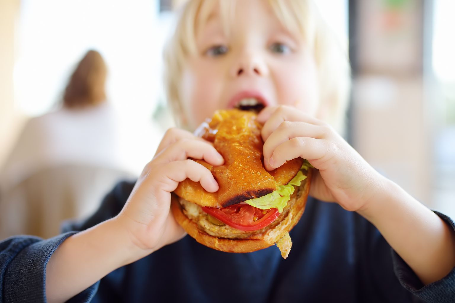 Ребенок ест гамбургер. Иллюстративное фото