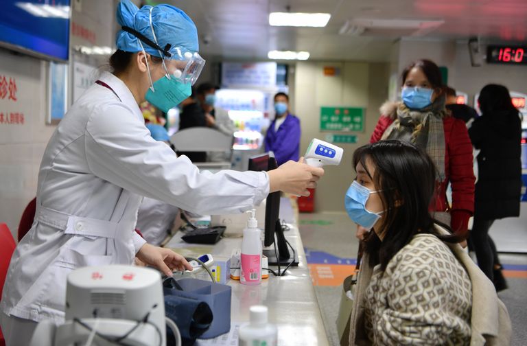 Hiina medtöötaja mõõtmas kehatemperatuuri, et teha kindlaks haiged inimesed, eelkõige need, kellel on uus koroonaviirus.