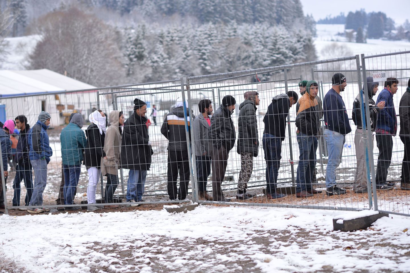 Migrandid Saksamaa ja Austria piiril ootavad järjekorras, et saada sooje riideid.