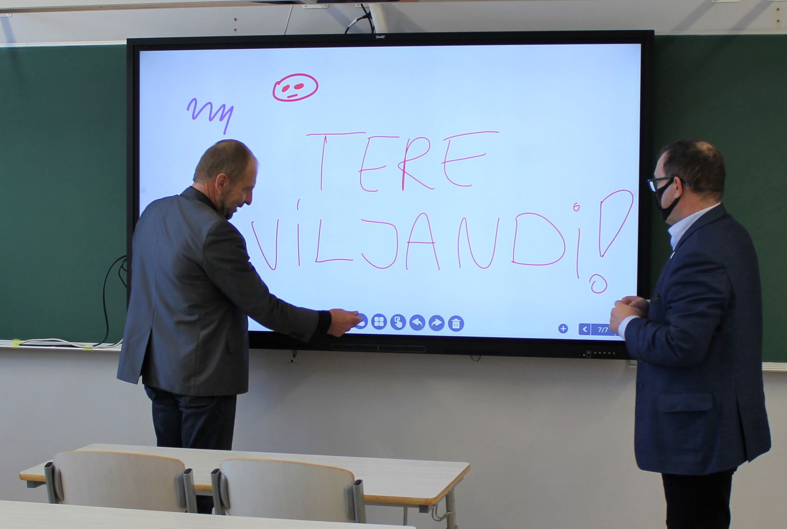 Kesklinna kooli haridustehnoloog Meelis Reinart (vasakul) ja Viljandi linnapea Madis Timpson uurivad interaktiivse tahvli vigureid.