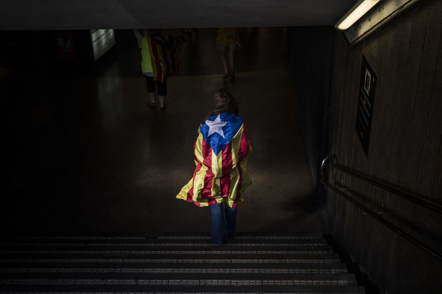 Kataloonia iseseisvuslippu mähitud naine Barcelona metroojaamas.